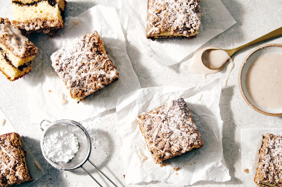 Cinnamon-Crisp Coffee Cake on parchment on a table dusted with sugar - select to zoom
