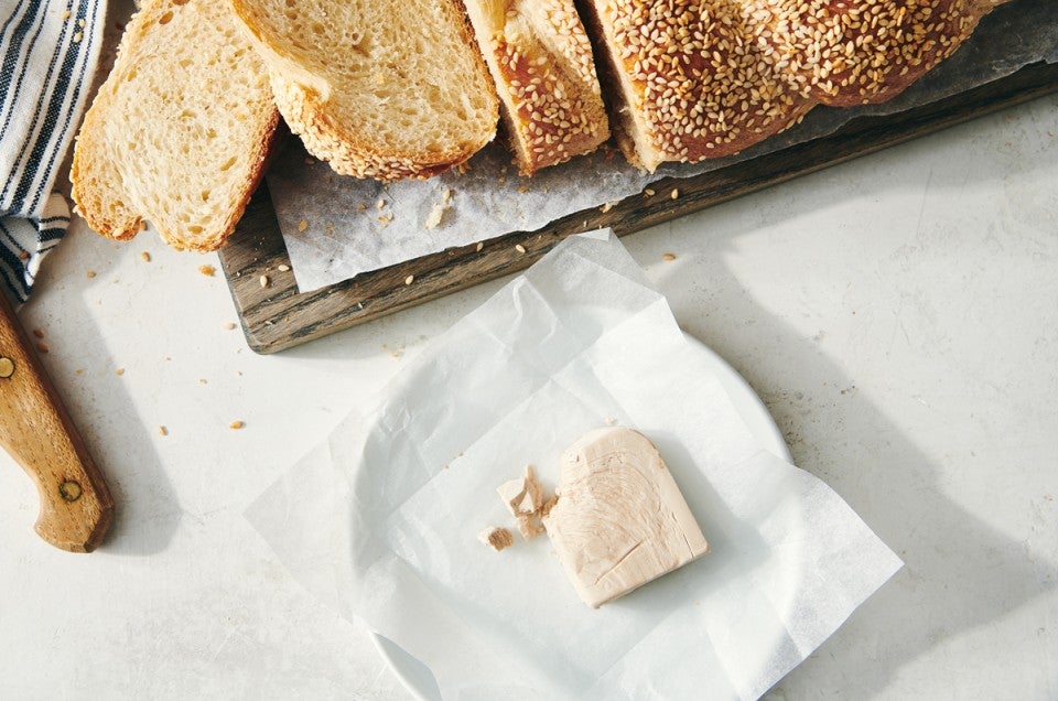 Block of fresh yeast in front of loaf of sliced bread