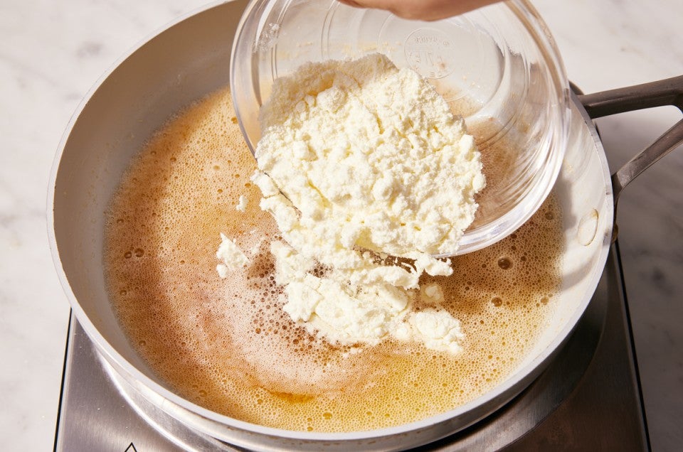 Baker pouring milk powder into browning butter