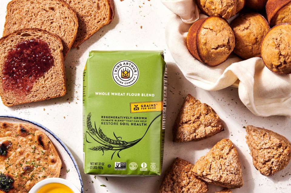 A bag of Climate Blend Flour surrounded by bakes goods made with it, including muffins, scones, flatbread, and sandwich bread