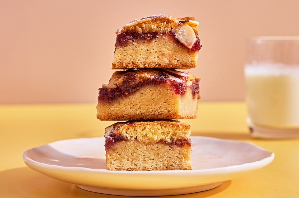 Raspberry Frangipane Bars stacked up on a plate - select to zoom