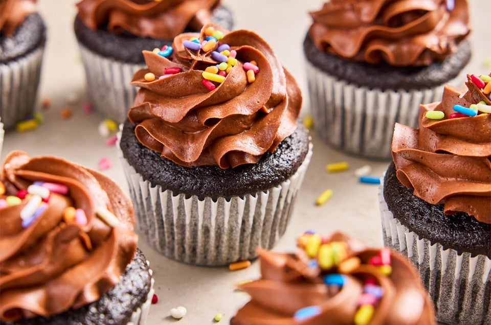 A bunch of Bake Sale Fudge Cupcakes topped with rainbow sprinkles - select to zoom
