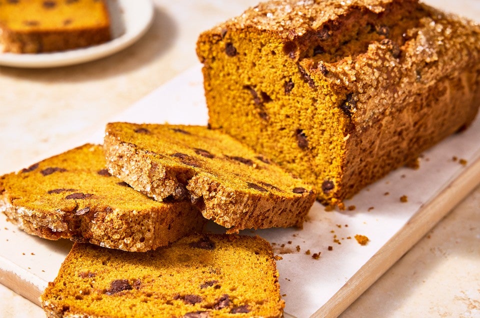 A loaf of The Most Pumpkin Pumpkin Chocolate Chip Bread with a few slices cut out of it - select to zoom