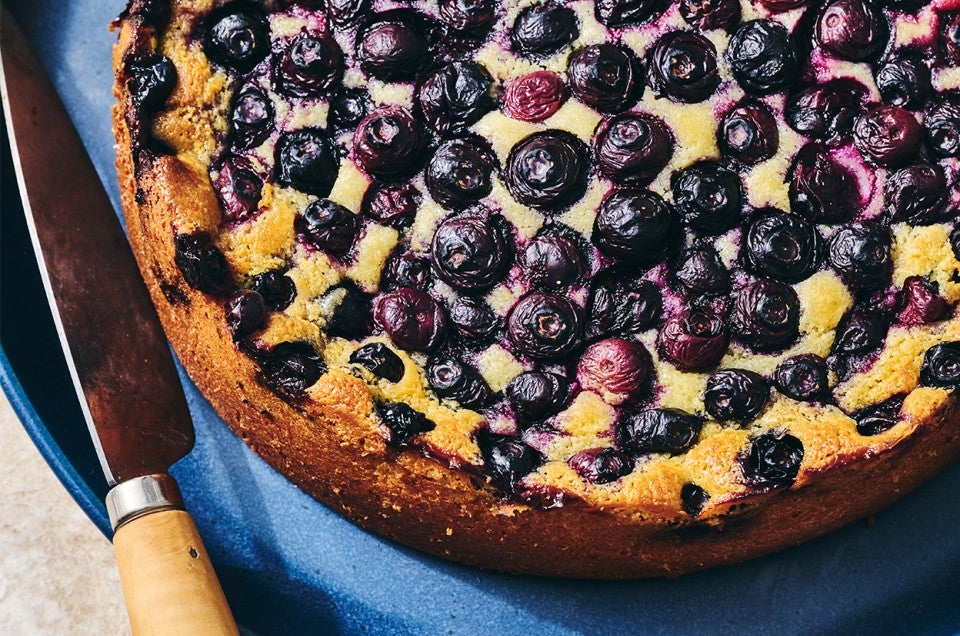An uncut Blueberry Breakfast Cake on a plate - select to zoom