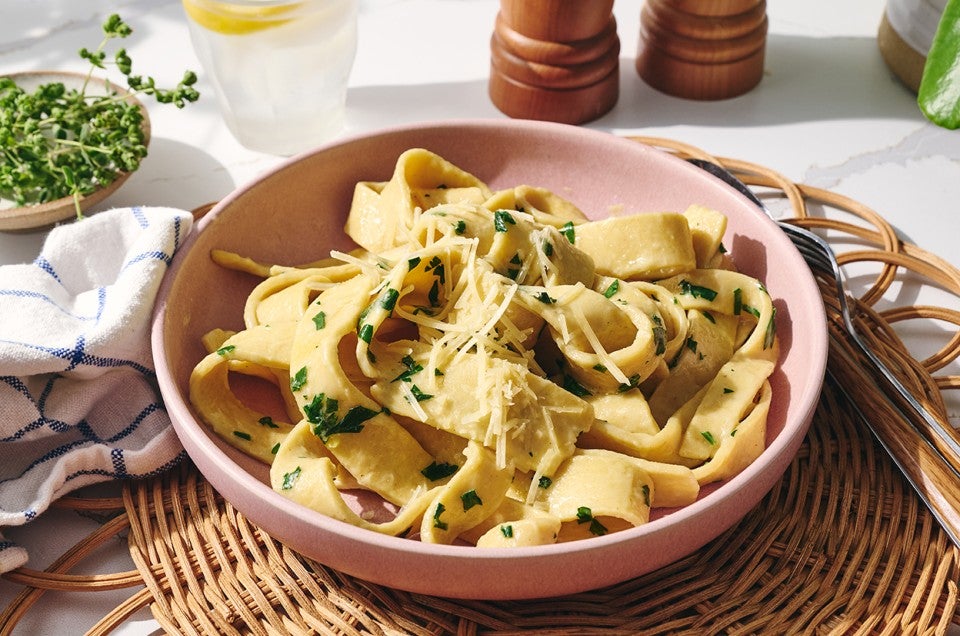Cooked gluten-free pasta in a pink bowl with herbs and cheese. - select to zoom