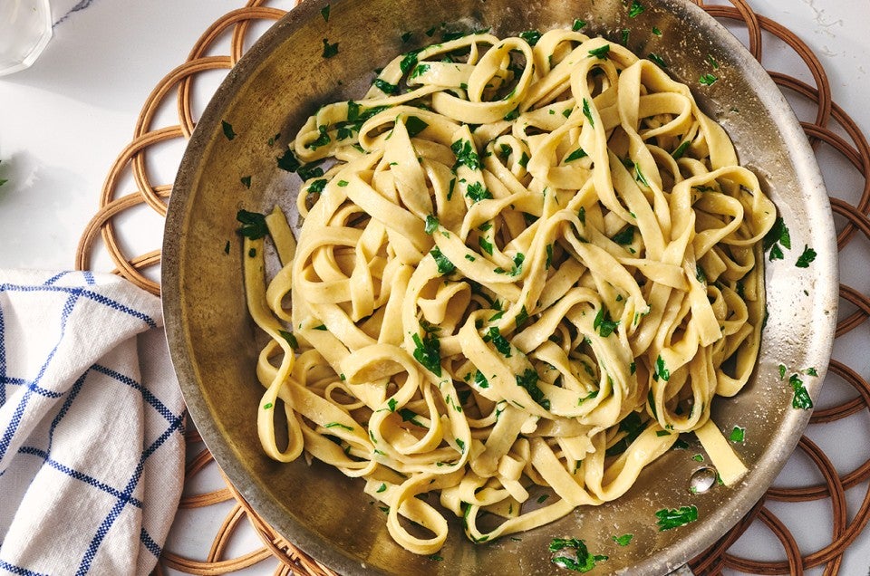 A bowl of gluten free pasta dressed with parmesan and parsley. - select to zoom