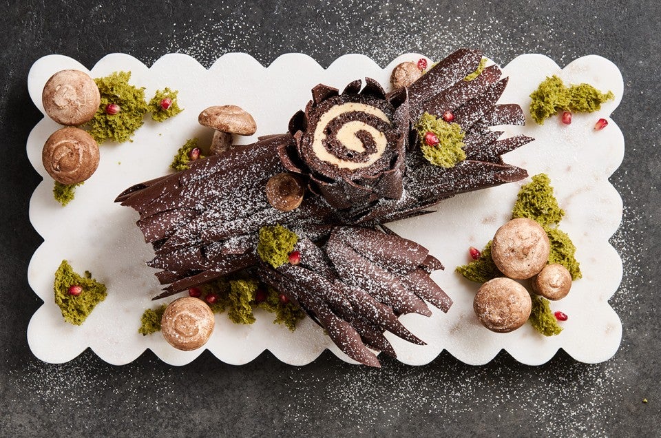 Chocolate Buche de Noel with Cookie Butter Whipped Ganache showing beautiful layers of chocolate coated cake and edible decorations in the style of a log. - select to zoom