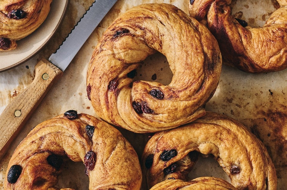 A handful of freshly baked Cinnamon Raisin Bagels on parchment paper seen from above. - select to zoom
