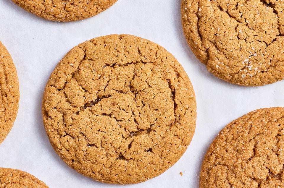 Soft Brown Sugar Cookies laid out on white parchment showing the top of the cookies with a soft cracked top and dark golden hues. - select to zoom