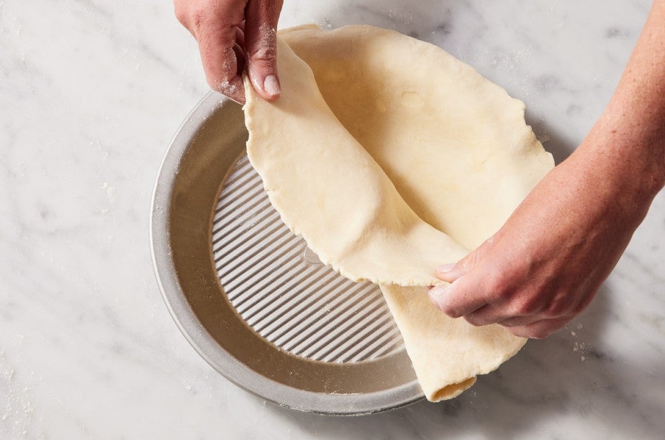 Placing pie crust dough in a pie pan 