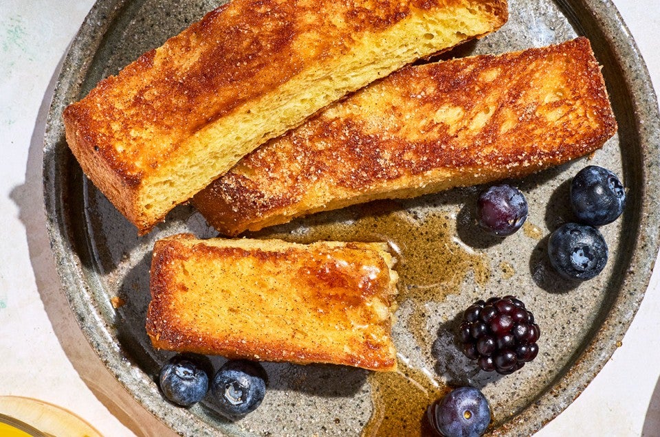 French Toast Sticks on a plate with fresh berries and maple drizzle. - select to zoom