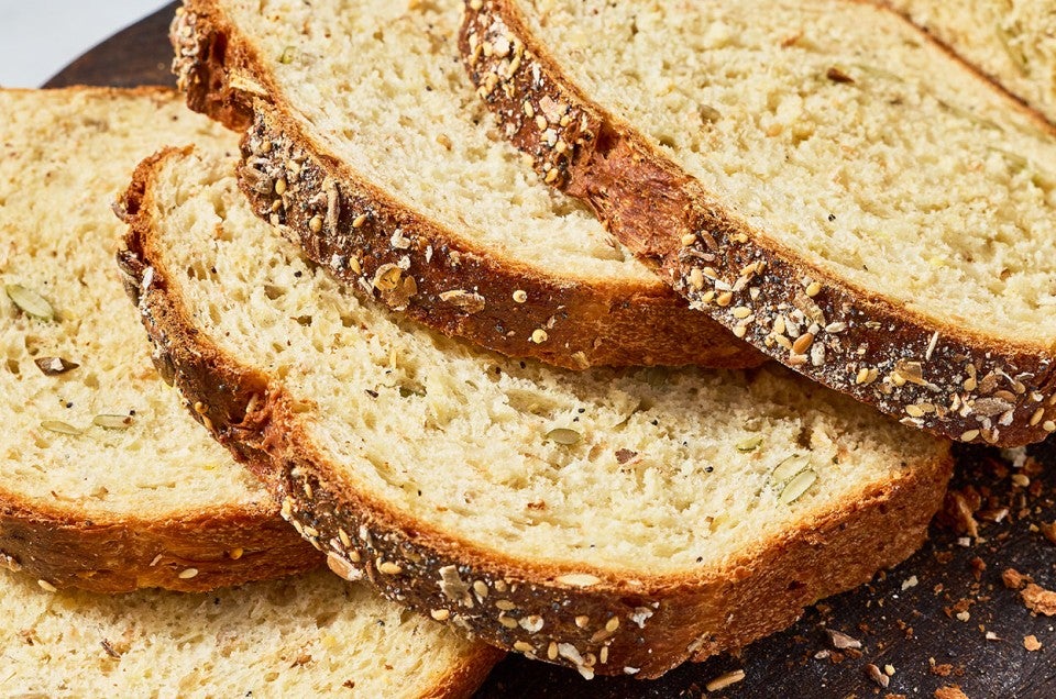 Slices of Multigrain Protein Bread arranged on top of each other showing the crust and golden interior. - select to zoom