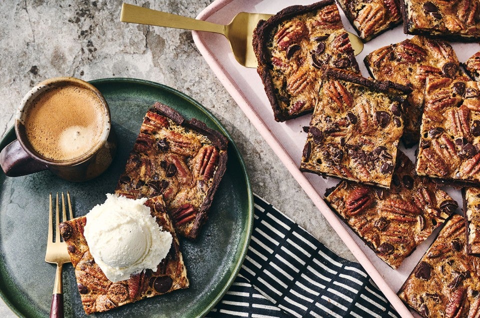 Two slices of Slab Chocolate Pecan Pie on a plate and one has vanilla ice cream on top. - select to zoom