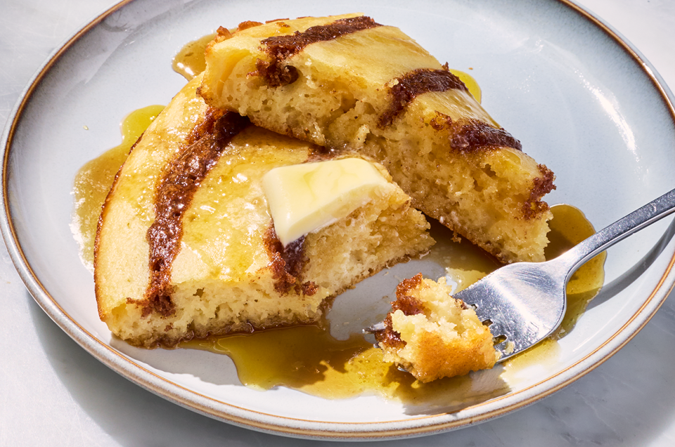 A Cinnamon Roll Skillet Pancake on a plate with some on a fork. - select to zoom