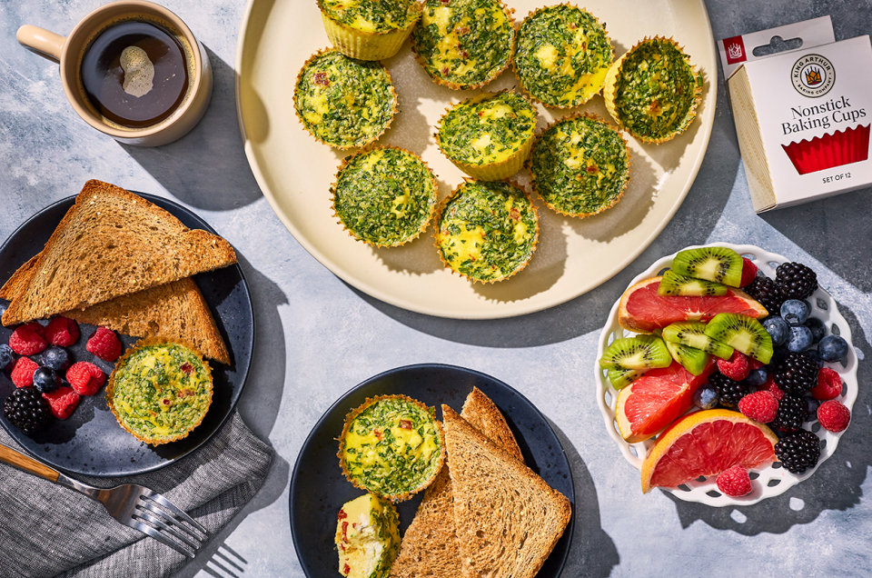 Egg Bites and breakfast spread with fresh fruit and toast on a counter. - select to zoom
