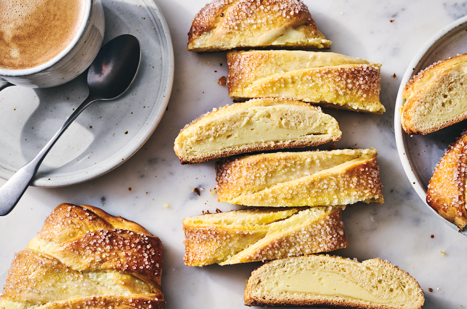 Cheese Filled Sweet Braid sliced on a counter with a cup of coffee in the corner. - select to zoom