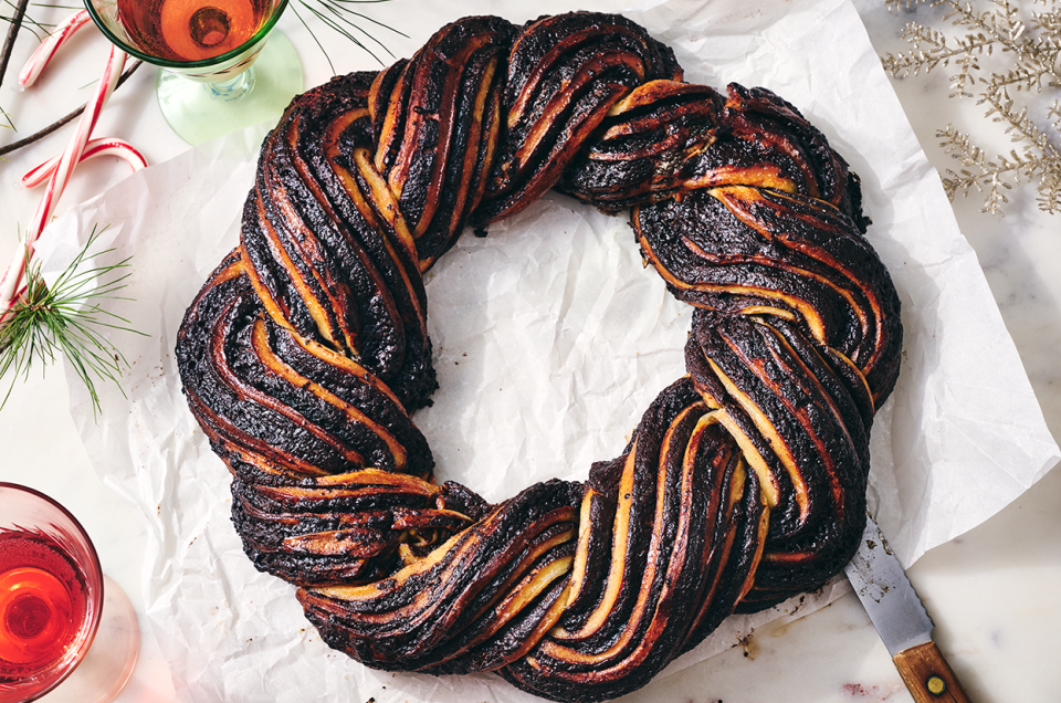 A full chocolate babka wreath on parchment paper on a countertop. - select to zoom
