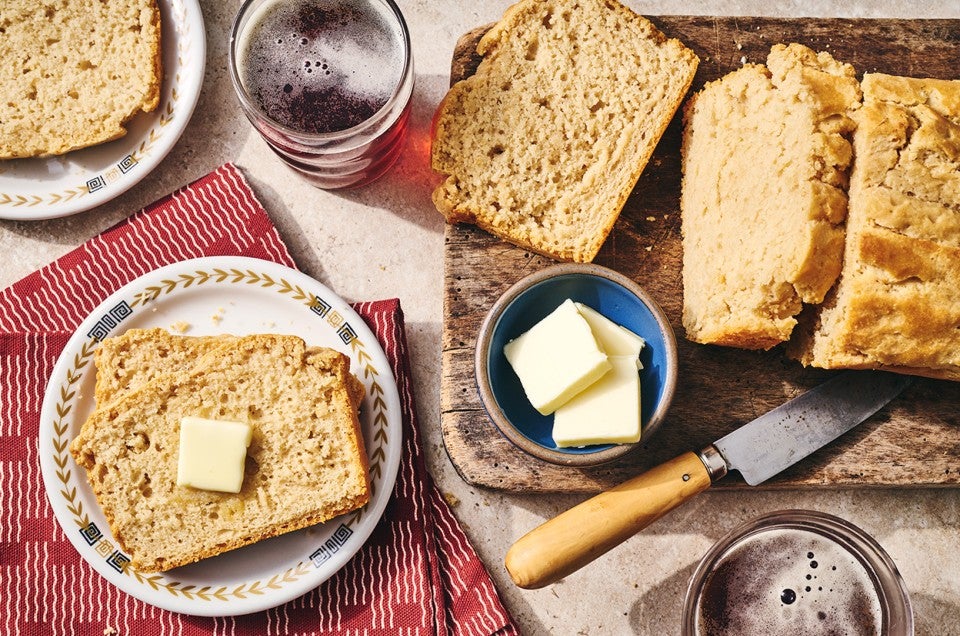 Sliced classic beer bread on a table with butter and a cutting board. - select to zoom
