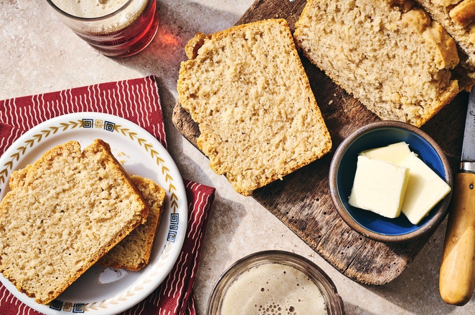 Sliced classic beer bread on a table with butter and a cutting board. - select to zoom