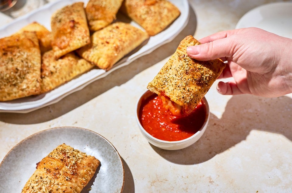 A Homemade Pizza Pocket being dipped in marinara sauce - select to zoom