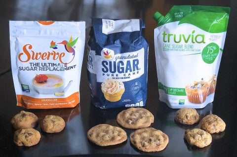 Bags of Swerve sugar replacement, granulated sugar, and Truvia Cane Sugar Blend, all pictured with chocolate chip cookies.
