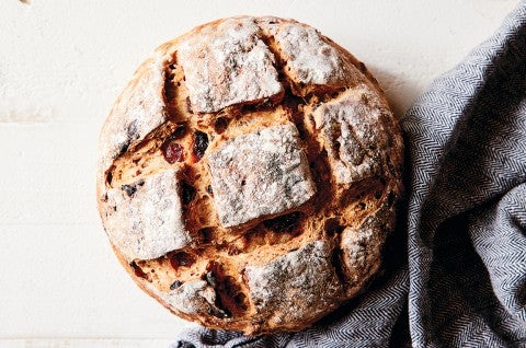 An artisan fruit bread with a crusty exterior and checkerboard pattern scored into the top.  - select to zoom
