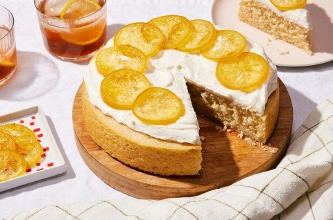 A simple, single layer lemon cake topped with frosting and candied lemon slices