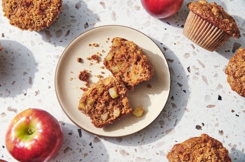 A freshly baked apple muffin split in half on a plate. - select to zoom
