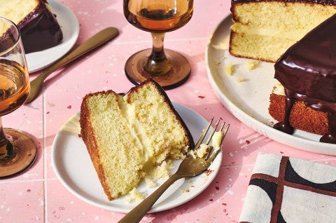 A slice of Boston Cream Pie on a plate with a fork and bite taken out of it. - select to zoom