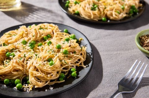 Whole Wheat Pasta with shredded cheese and peas on a dinner plate - select to zoom