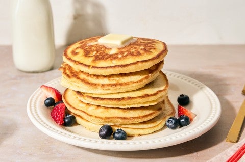 Easy Buttermilk Pancakes stacked high on a plate with fresh fruit - select to zoom