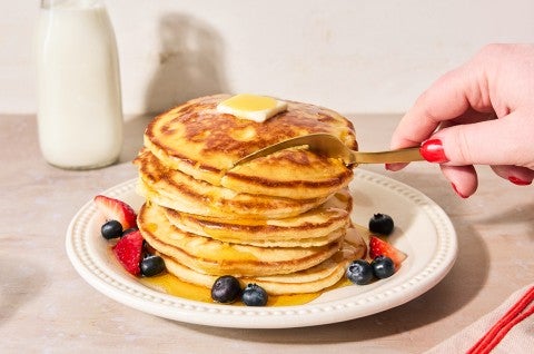 Easy Buttermilk Pancakes topped with maple syrup on a plate with fresh fruit - select to zoom