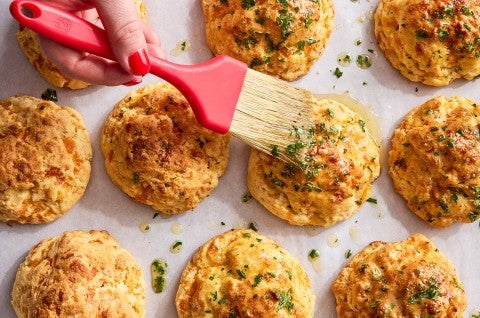 Garlic Cheddar Biscuits being brushed with butter - select to zoom
