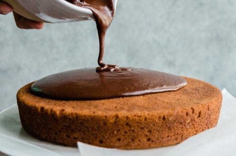 Yellow cake with fudge frosting being poured over it - select to zoom