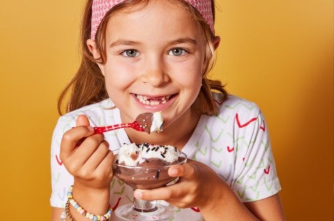 A little girl eating chocolate pudding