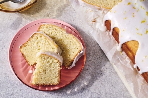 2 slices of Glazed Sourdough Lemon Cake on a plate next to the full loaf - select to zoom