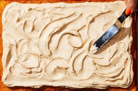 Silky frosting being applied to a cake with an offset spatula