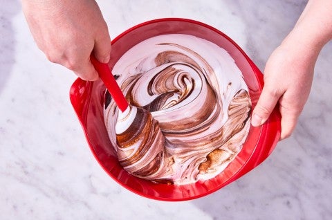 Folding cake batter in red mixing bowl