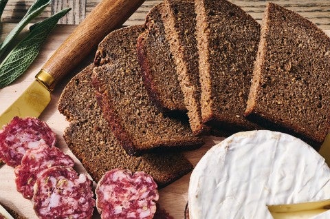 Classic Pumpernickel Bread sliced on a cutting board with meat and cheese - select to zoom