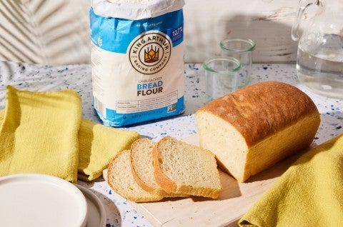 Sliced sourdough sandwich bread next to bag of bread flour