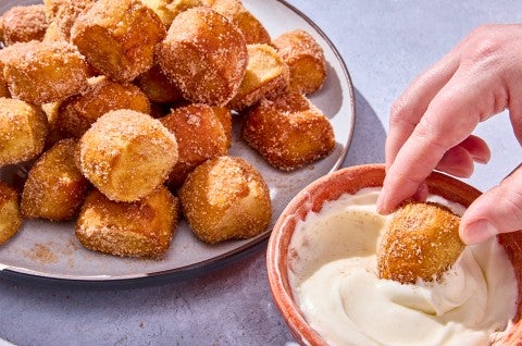 A Cinnamon-Sugar Pretzel Bite being dipped - select to zoom