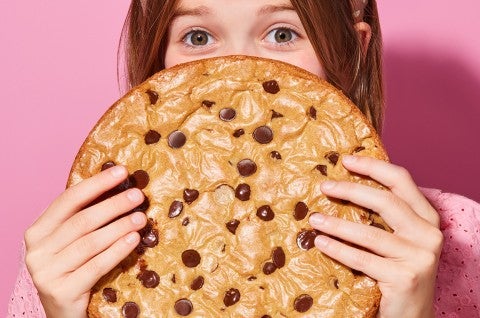 A young girl hiding behind a Chocolate Chip Skillet Cookie - select to zoom