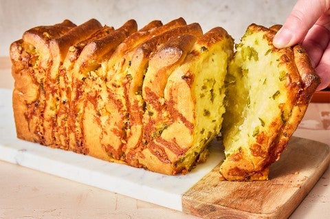 A slice of Jalapeño-Cheddar Pull-Apart Bread being pulled from the loaf - select to zoom