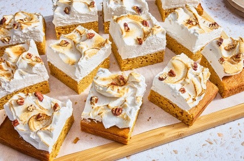 A bunch of Sweet Potato Sheet Cake with Marshmallow Frosting cut into slices on a cutting board - select to zoom