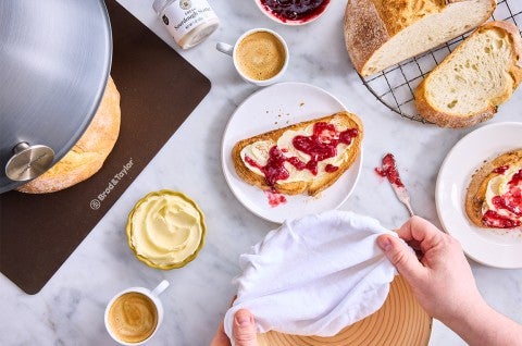Extra-Tangy Sourdough Bread sliced on a plate with butter and jam - select to zoom
