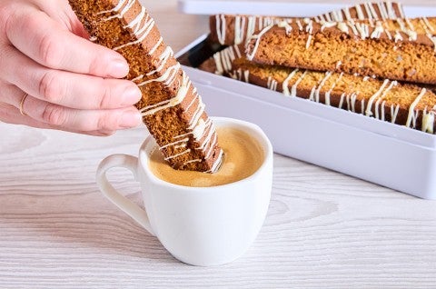 A piece of Gingerbread Biscotti being dipped into coffee - select to zoom