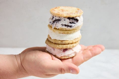 Three sandwich bread ice cream sandwiches stacked on top of each other in a baker's hand