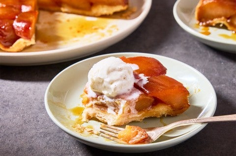 A slice of Classic Apple Tarte Tatin on a plate with a scoop of vanilla ice cream on top - select to zoom