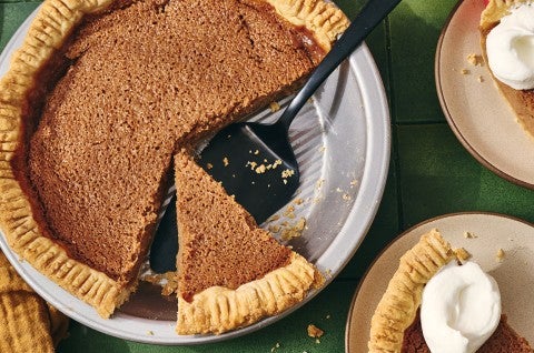 A slice of apple pie in the pie tin shown with a spatula under it and two slices on plates next to it. - select to zoom
