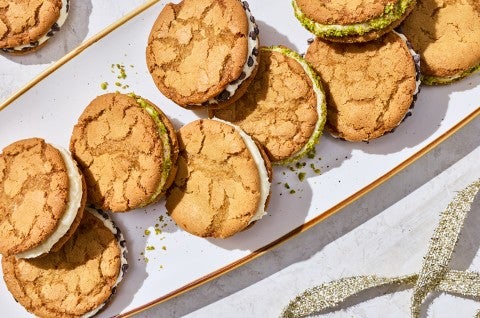Looking down on a festive plate of cannoli sandwich cookies with cracked tops and crumbs of pistachios. - select to zoom